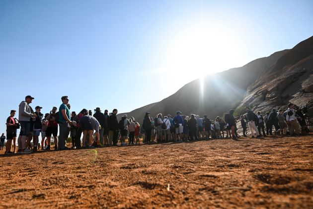 Tourists line up waiting to climb the sandstone monolith called Uluru 