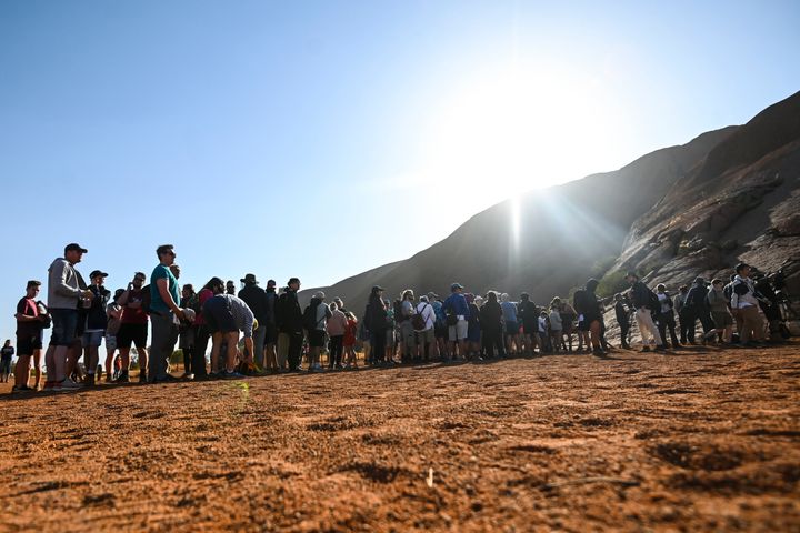 Tourists line up waiting to climb the sandstone monolith called Uluru 