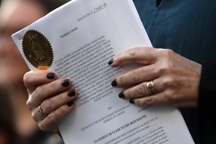 A lawyer holds the documents filed on behalf of the 15 young people who are parties to a lawsuit against the federal government for contributing to high levels of greenhouse gas emissions and dangerous climate change during a rally in Vancouver on Friday.