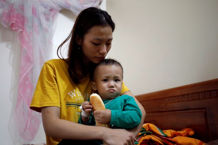 Hoang Thi Thuong, wife of Nguyen Dinh Tu, a Vietnamese suspected victim in a truck container in UK, holds her son Nguyen Dinh Dan at their home in Nghe An province, Vietnam October 26, 2019. REUTERS/Kham