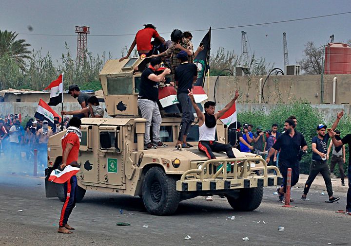Protesters ride an Iraqi Army armored vehicle during a demonstration in Basra, Iraq, Friday, Oct. 25, 2019. After a week of violence in the capital and the country's southern provinces, a government-appointed inquiry into the protests determined that security forces had used excessive force. (AP Photo/Nabil al-Jurani)