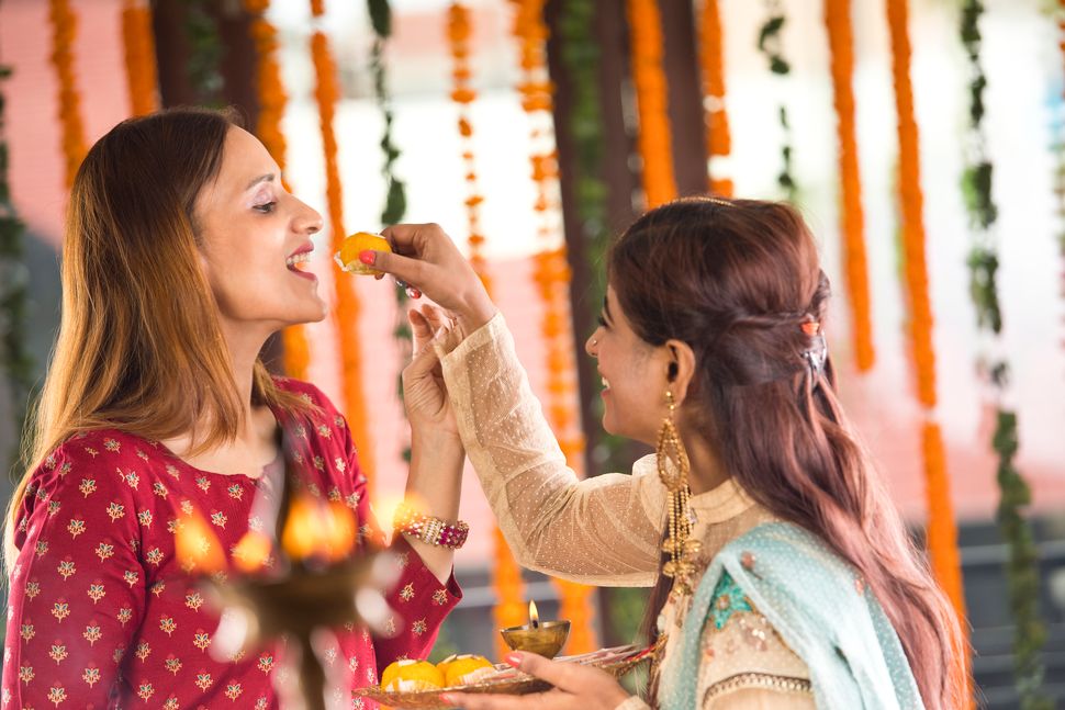 Indian woman feeding sweet food to her sister-in-law on the occasion of traditional festival