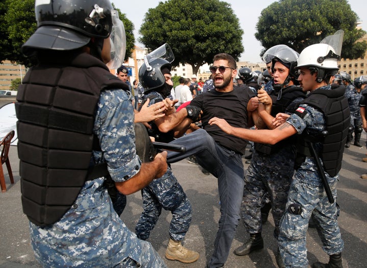 Police remove an anti-government protester blocking a main highway with his body in Beirut, Lebanon, Saturday, Oct. 26, 2019.
