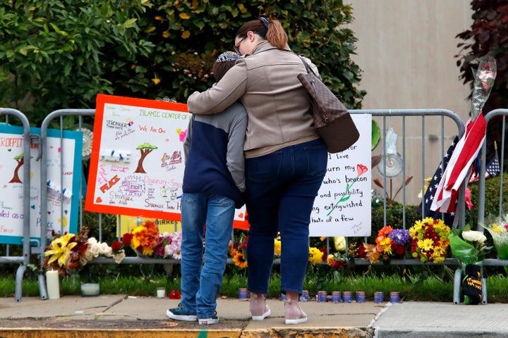 A mother hugs her son in front of a memorial at the Tree of Life synagogue in Pittsburgh on Sunday, Oct. 27, 2019, the first anniversary of the shooting at the synagogue, that killed 11 worshippers. 