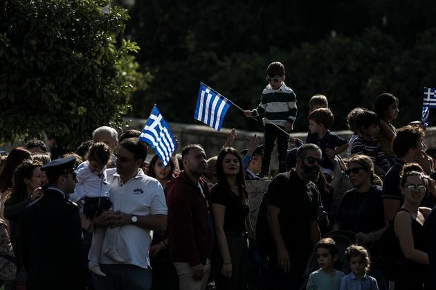 Μικροί και μεγάλοι καμαρώνουν τους μαθητές που παρελαύνουν.