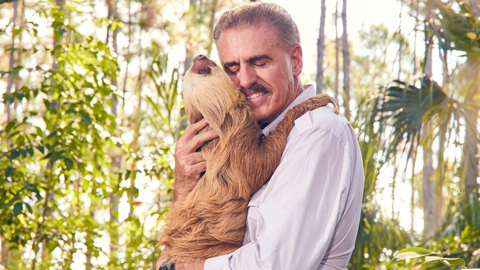 Ron Magill of Zoo Miami cuddles with a Hoffmann's two-toed sloth named Chelsea.