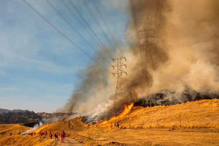 A back fire burns a hillside near PG&E power lines during firefighting operations to battle the Kincade fire in Healdsburg, in Northern California's Wine Country.