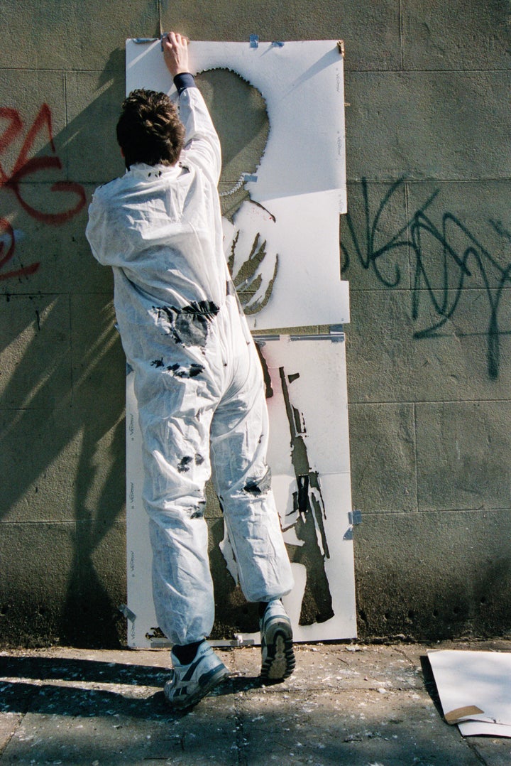 Banksy, pictured by Lazarides, putting up his "Pissing Copper" piece.