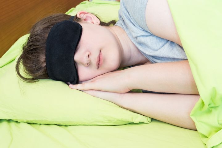 girl teenager in black mask sleeps on green linen