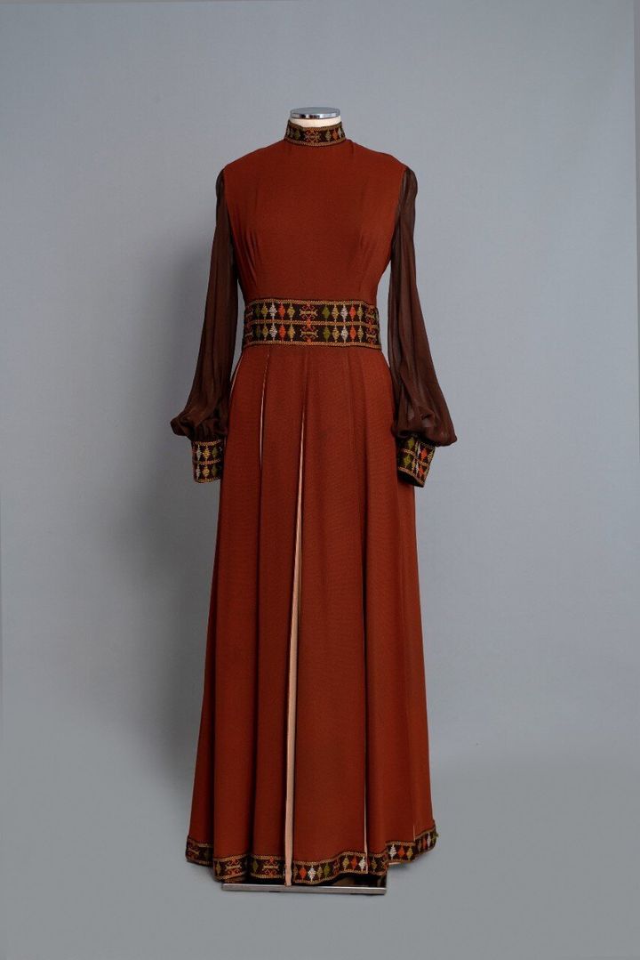 1970-36. Φόρεμα μάξι από καφέ κρεπ με ενυφασμένα γεωμετρικά σχέδια του οίκου «Nikos-Takis». Δεκαετία 1970. Δωρεά: Νένα Σακελλαροπούλου