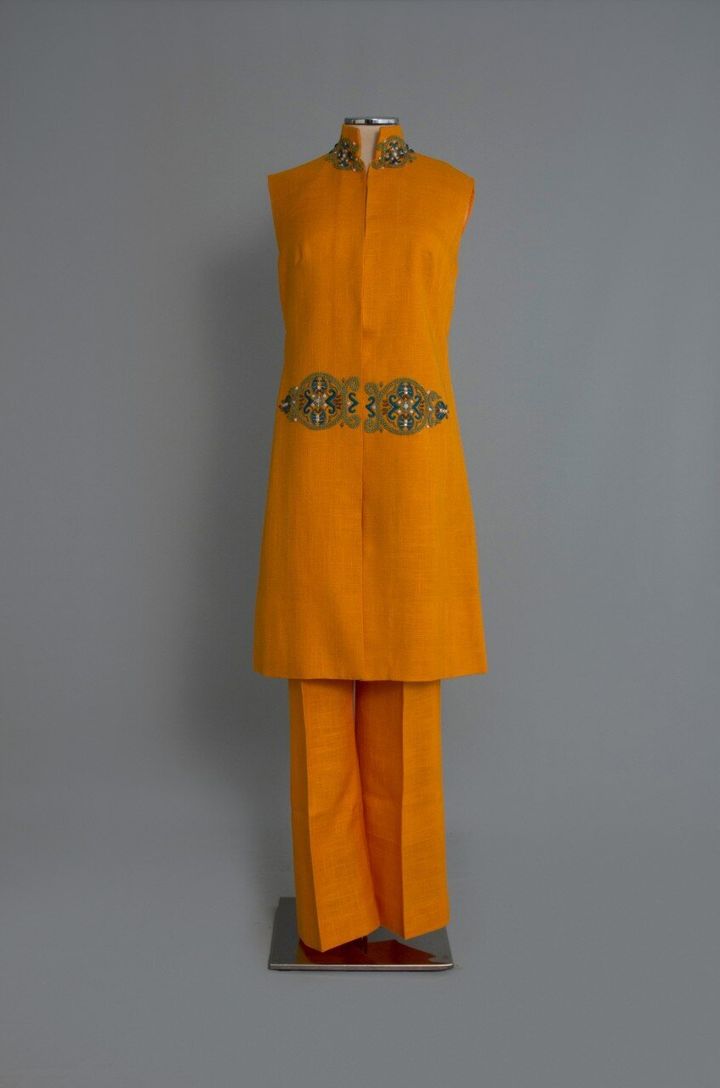 1960-12. Σύνολο από πορτοκαλί λινό ύφασμα της Cleo’s Art Souvenirs με κεντημένη «πόρπη». Αθήνα. Δεκαετία 1960. Δωρεά: Κλειώ Μποσταντζόγλου