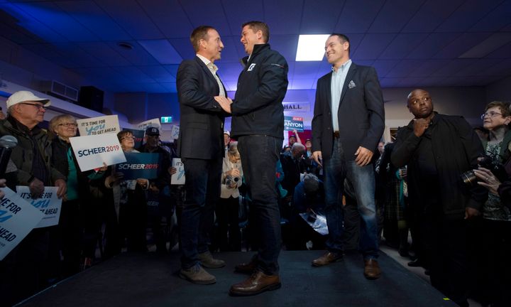 Local conservative candidate George Canyon, right, looks on as Conservative leader Andrew Scheer, centre, shakes hands with Peter MacKay during a campaign stop in Little Harbour, N.S. on Oct. 17, 2019.