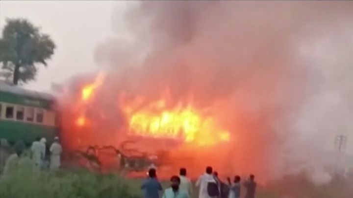 People watch fire burning a train after a gas canister passengers were using to cook breakfast exploded, near the town of Rahim Yar Khan in the south of Punjab province, Pakistan October 31, 2019, in this still image take from video. 