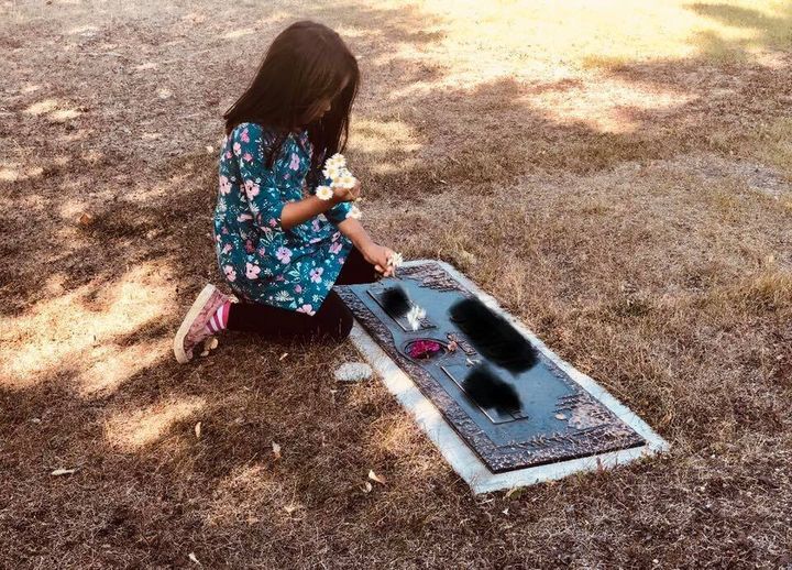 Leah Campbell's daughter arranging flowers at the grave they chosen to represent the father she never met.