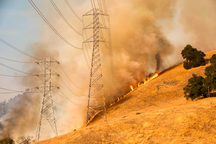 Firefighters battle flames behind PG&E power lines in Healdsburg, California, on Oct. 26.