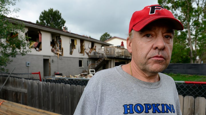 Leo Lech stands on a pile of wood in his neighbor's yard that overlooks the back of his condemned home in June 2015.