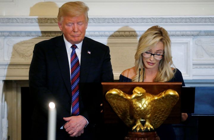 President Donald Trump closes his eyes as the Rev. Paula White leads a prayer at a dinner hosted by the Trumps at the White House August 27, 2018.
