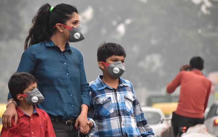 A woman and children wearing anti-pollution masks to protect against air pollution at Old Railway Road near Jail Chowk, on November 2, 2019 in Gurugram, India. 