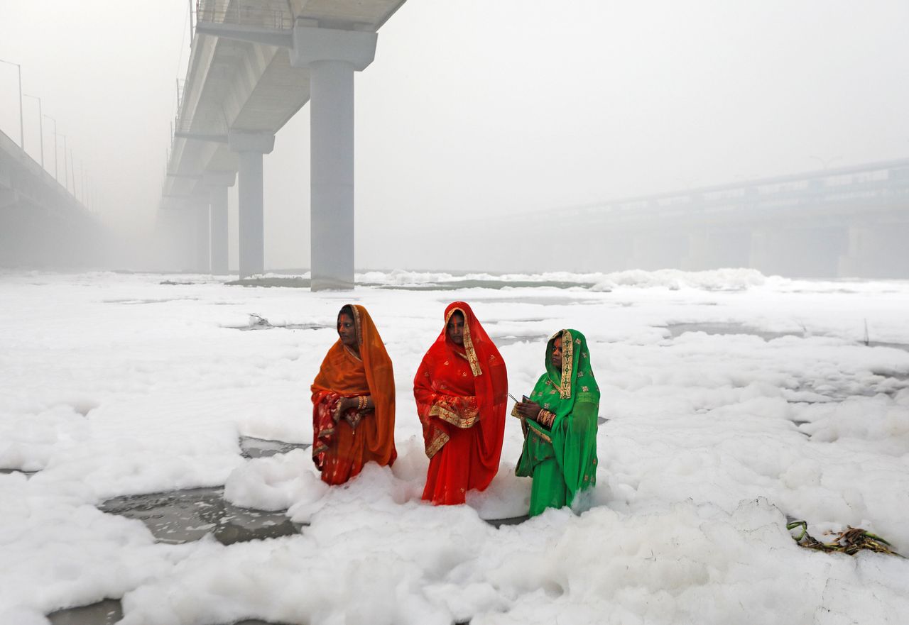 It looks like snow - but it's industrial waste. Hindu women worship the Sun god in the polluted waters of the river Yamuna during the religious festival of Chhath Puja