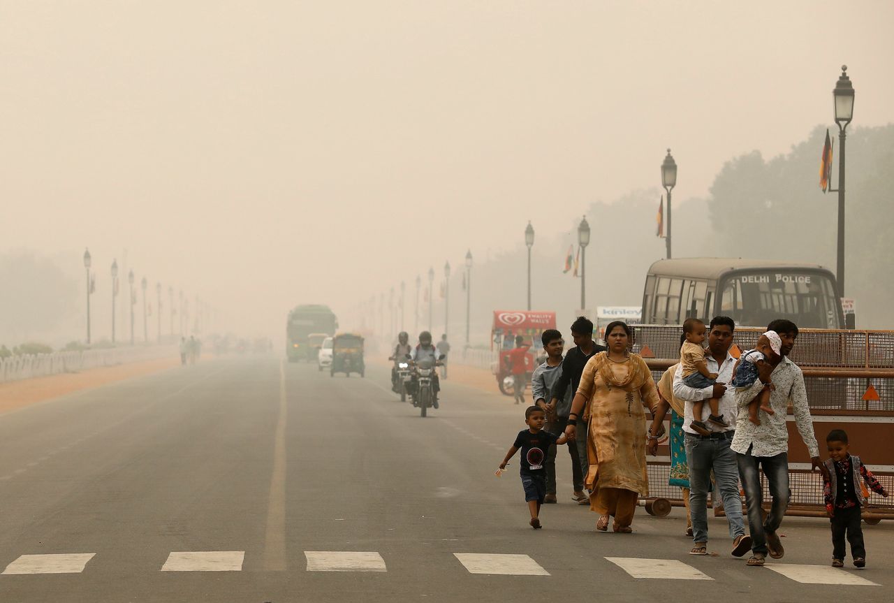 People walk on the Rajpath on a smoggy day in November