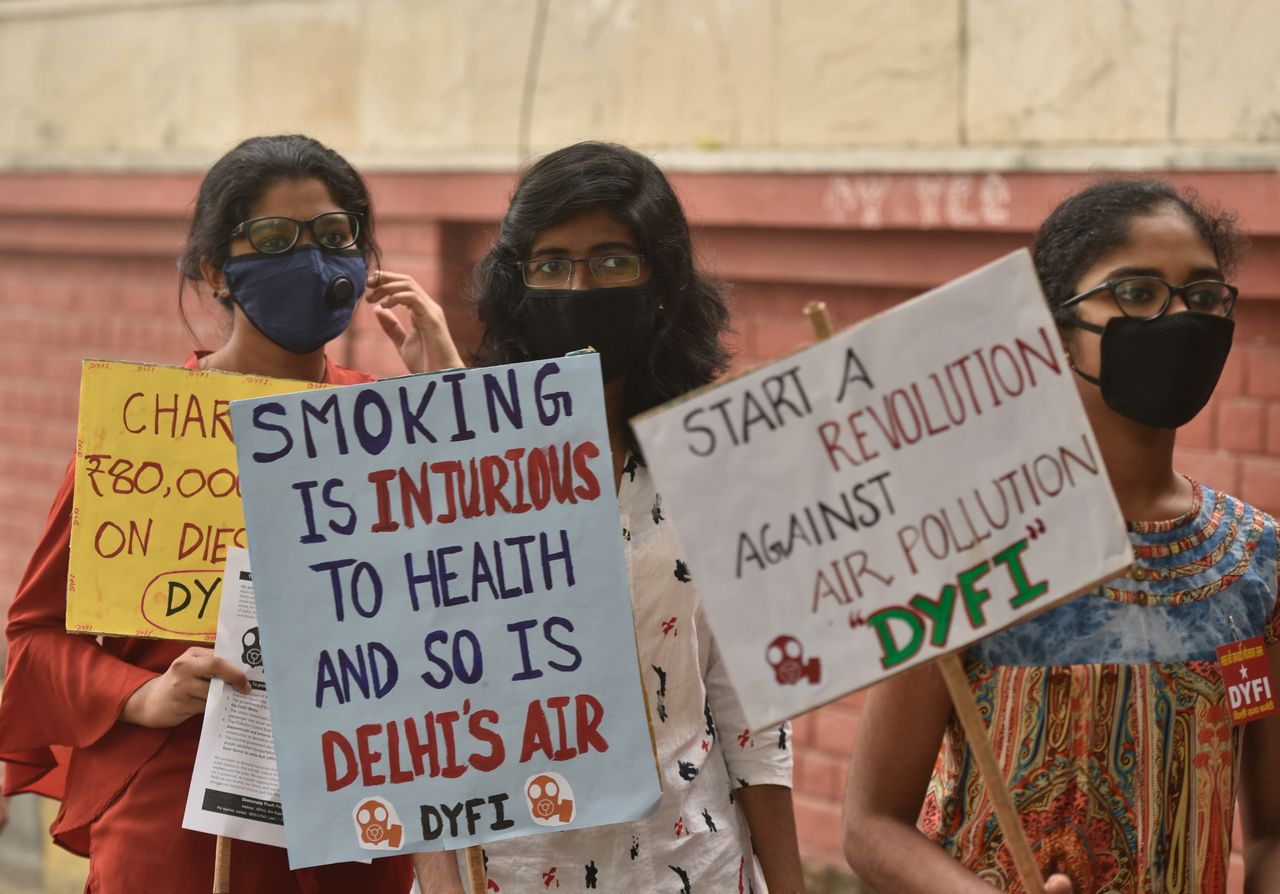Protesters wearing masks display placards during a march demanding implementation of measures to reduce air pollution.