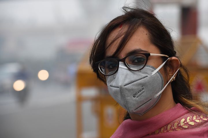 A woman wearing a protective face mask waits for public bus in New Delhi. 