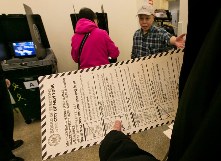 In this Nov. 4, 2014 file photo, a voter carries her ballot to be scanned at a polling place in New York's Chinatown neighborhood. 