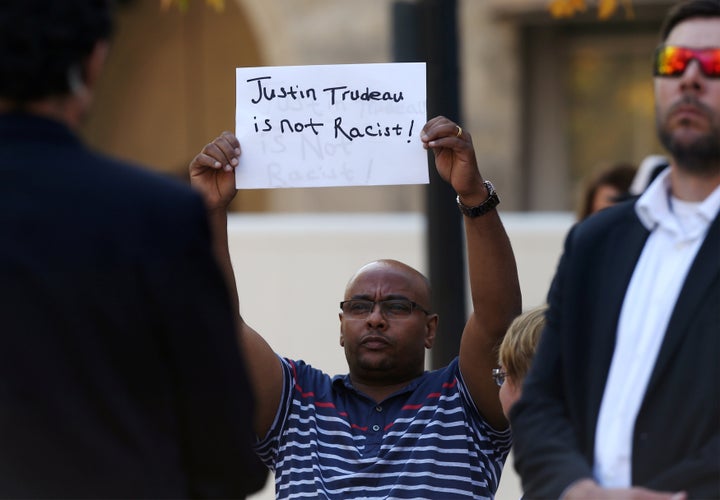 A man holds a sign that reads "Justin Trudeau is not racist" as the Liberal leader spoke in Winnipeg on Sept. 19, 2019.