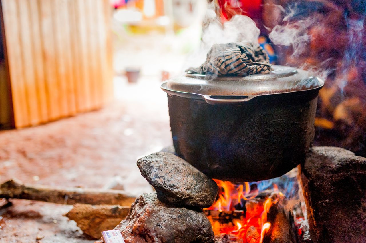 smoking iron pot above fire in traditional african kitchen in cameroon during cooking