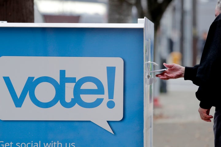 A voter drops a ballot into a ballot drop box Monday, Nov. 4, 2019, in Seattle. 