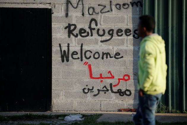 Un migrante cruza ante una pintada de bienvenida en Calais (Francia), en
