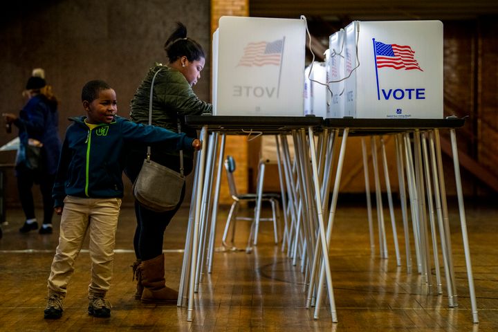 Amari Hardy, 7, plays alongside his mother, TaQuisha Hardy, of Flint, as she casts her ballot on Election Day, Tuesday, Nov. 5, 2019, at Berston Field House in Flint, Mich. (Jake May/The Flint Journal via AP)
