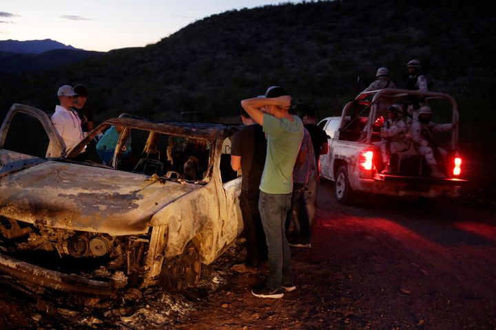 Relatives of slain members of Mexican-American families belonging to Mormon communities observe the burnt wreckage of a vehicle where some of their relatives died.