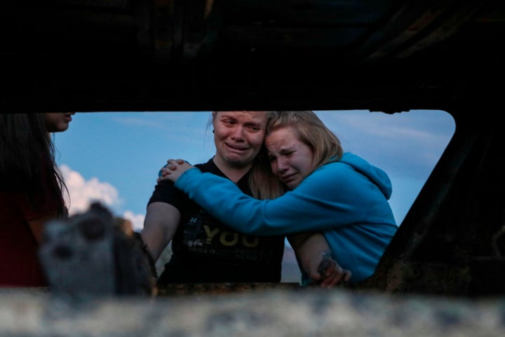 Family members mourn near a car burned during an ambush in the Sonora mountains, Mexico, on Nov. 5, 2019.