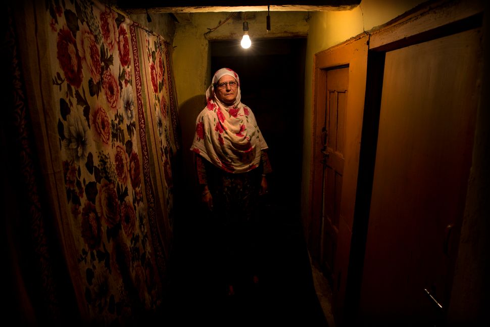 In this Sept. 25, 2019, photo, Ateeqa Begum, mother of a 22-year-old Kashmiri detainee Fasil Aslam Mir, stands for a photograph inside her house in Srinagar. Begum has lived alone ever since her only son Fasil, in his late twenties, was detained on his way home after fetching medicines for her. 