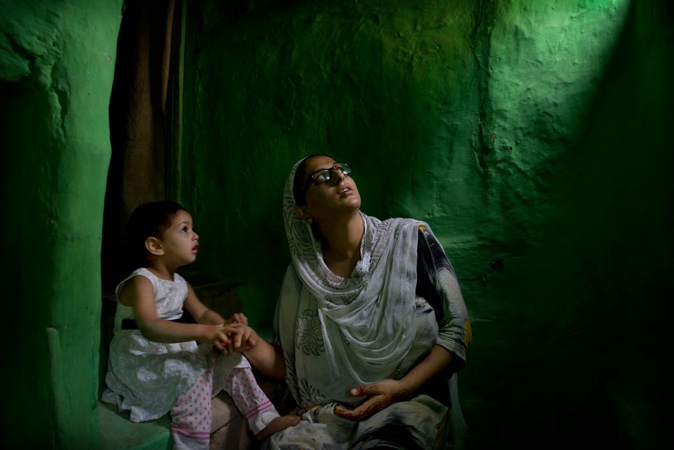 In this Sept. 27, 2019, photo, Sumaira Bilal, wife of Kashmiri detainee Bilal Ahmed, talks to her two-year-old daughter as they sit for photographs on a staircase of their house in Srinagar. Ahmed was detained on the night of Aug. 5, the day Modi government repealed Article 370 of the Indian Constitution, stripping Kashmir of its statehood. Sumaira says her daughter points to the window often and calls for her father “Baba, Baba, when are you coming back?” 