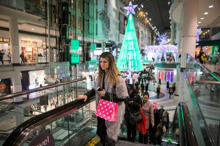 Holiday shoppers make their way through Toronto's Eaton Centre on Dec. 14, 2015. A new survey found nearly half of Canadians overspent on holiday purchases last year.