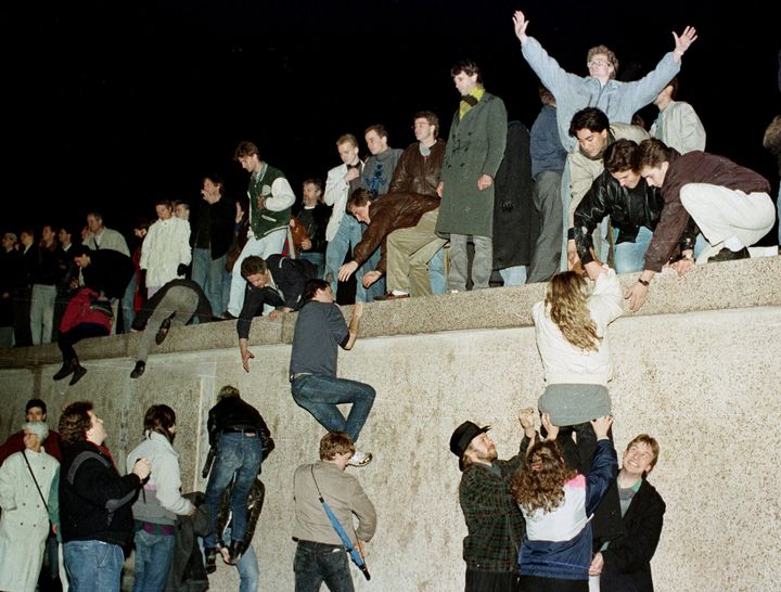 People climb the Berlin wall at the Brandenburg Gate as they celebrate the opening of the East German border November 9, 1989.