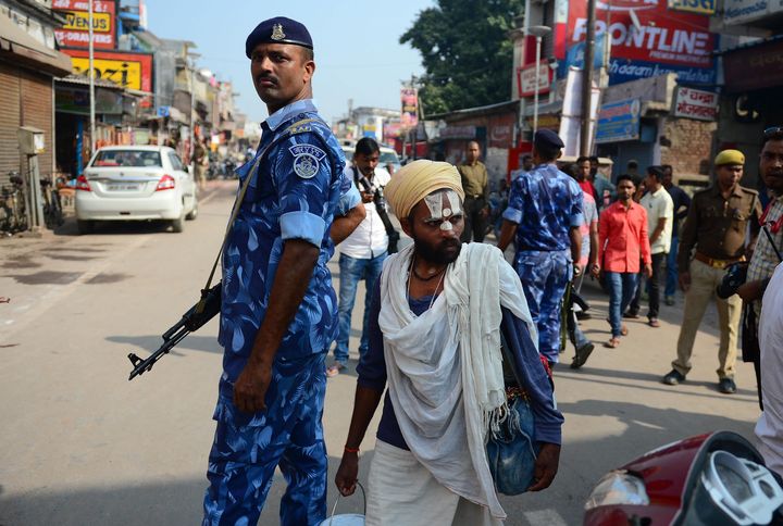A man walks past security personnel on a road in Ayodhya on November 9, 2019, ahead of a Supreme Court verdict on the disputed religious site.