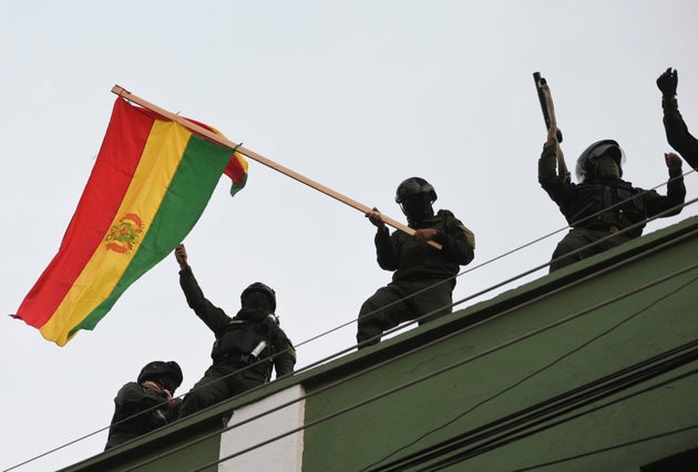 Police officers wave a national flag while standing on the roof of their headquarters, in Cochabamba, Bolivia November 8, 2019.  REUTERS/Danilo Balderrama
