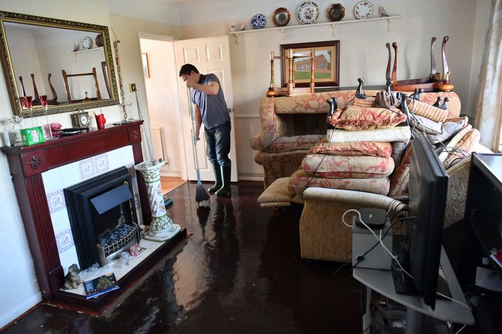 Paul Croucher mops his parents' living room after it was flooded in Fishlake, Doncaster.