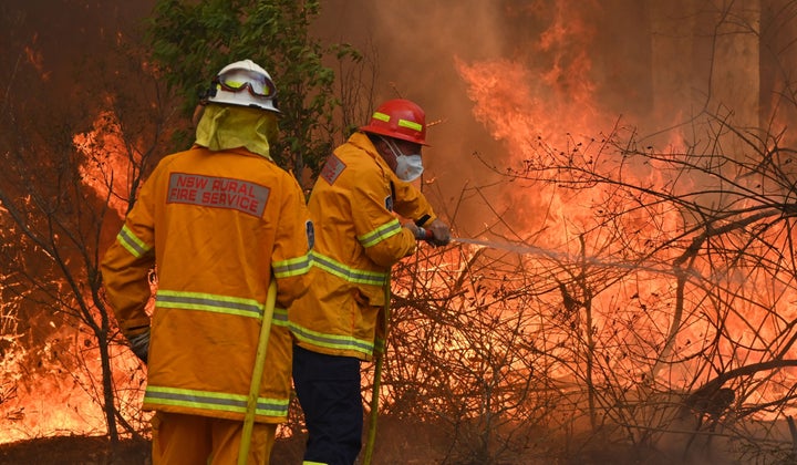 Firefighters tackle a bushfire to save a home in Taree, NSW on Saturday.