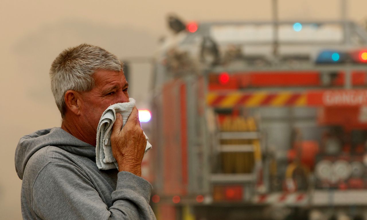 A resident watches the progress of bushfires near houses in Old Bar, New South Wales.
