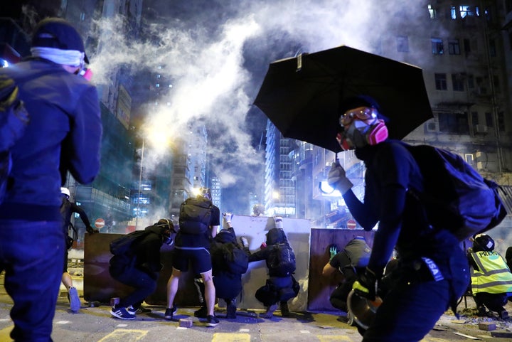 Protesters take cover behind boards during a protest in the Mong Kok area in Hong Kong, China November 11, 2019. (REUTERS/Tho