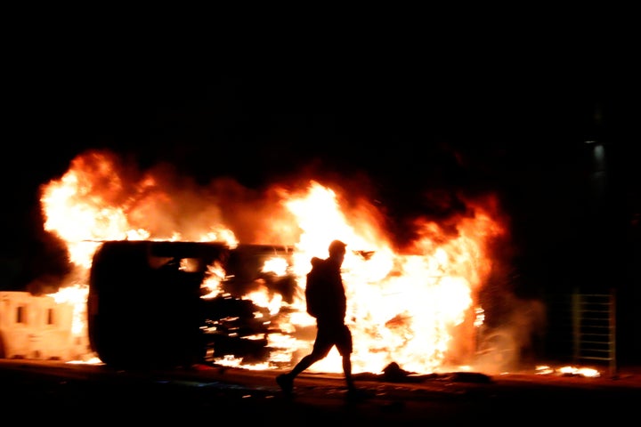 An anti-government protester walks past a burning vehicle during a protest in Tseung Kwan O, Hong Kong, China November 11, 20