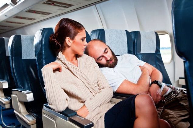 機内で寝ている男性が女性に寄りかかる様子 イメージ写真