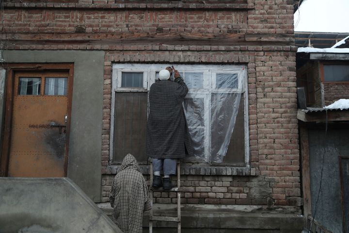 Kashmiri men fix polytene sheets outside their home to protect from cold in Srinagar, India, Sunday, Nov. 10, 2019.(AP Photo/ Mukhtar Khan)