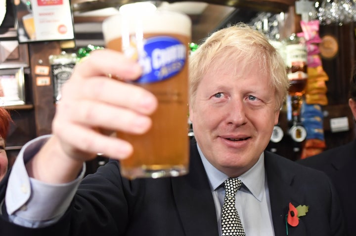 Prime Minister Boris Johnson, raises a pint as he meets with military veterans at the Lych Gate Tavern in Wolverhampton on the campaign trail.