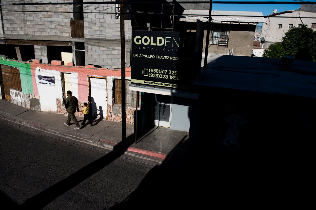 A dental worker, one of hundreds in the city, walks hand in hand with a child in the early morning in Los Algodones, Baja California, Mexico, on Oct. 23, 2019.