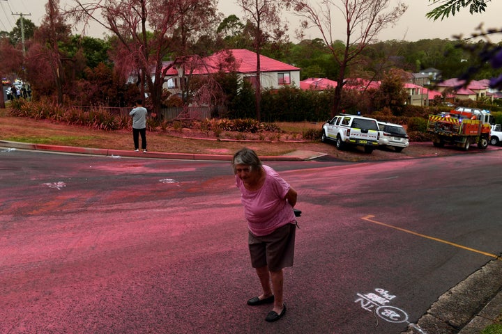 A resident walks infront of South Turramurra homes which were bombed by fire-retardant during NSW RFS firefighting efforts in Sydney.